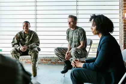 Military veterans engage in a supportive group therapy session with a mental health professional.