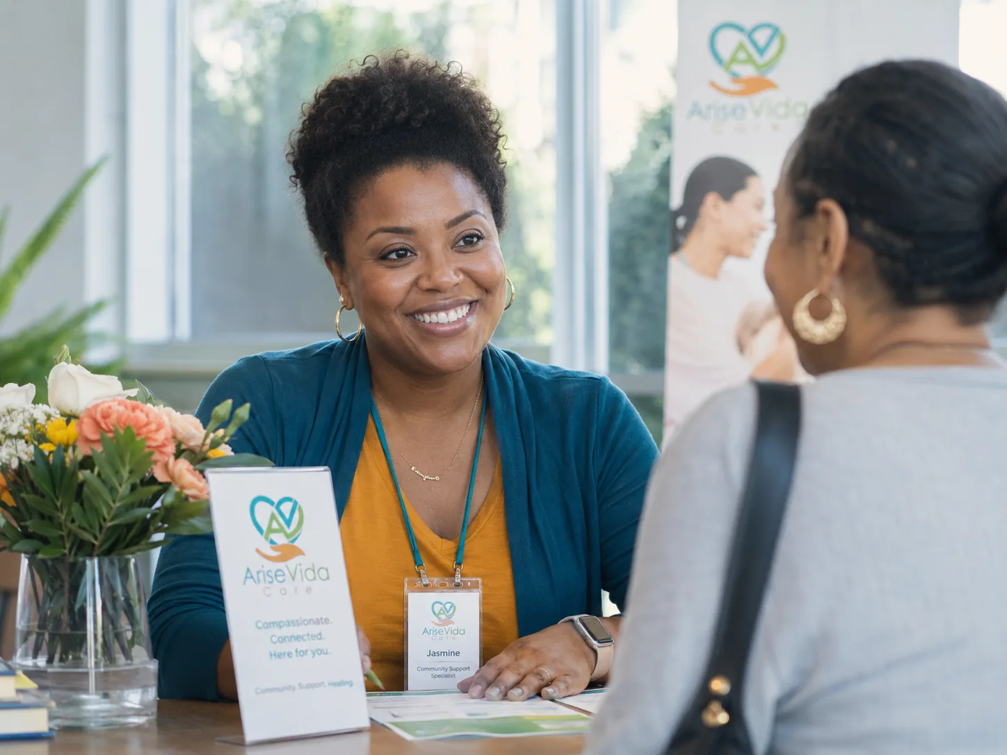 An AriseVida Care team member helping a visitor at the front desk, reviewing information together.