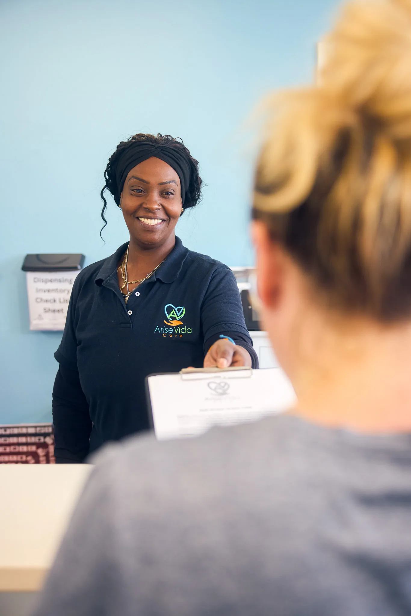 A warm AriseVida Care team member welcoming an adult patient and reviewing intake materials in a calm outpatient setting.