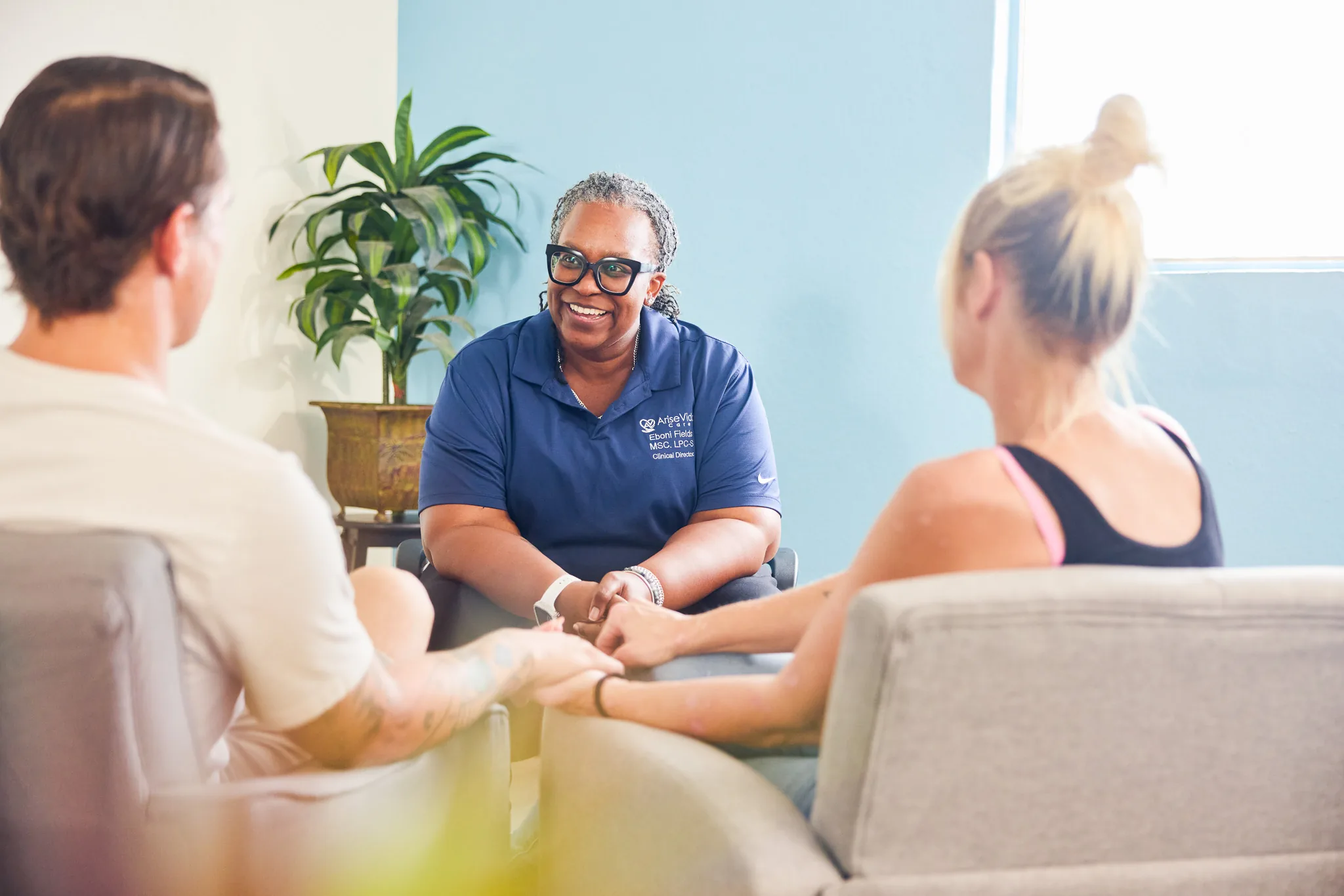 An AriseVida Care team member in a warm, supportive session with two adults.