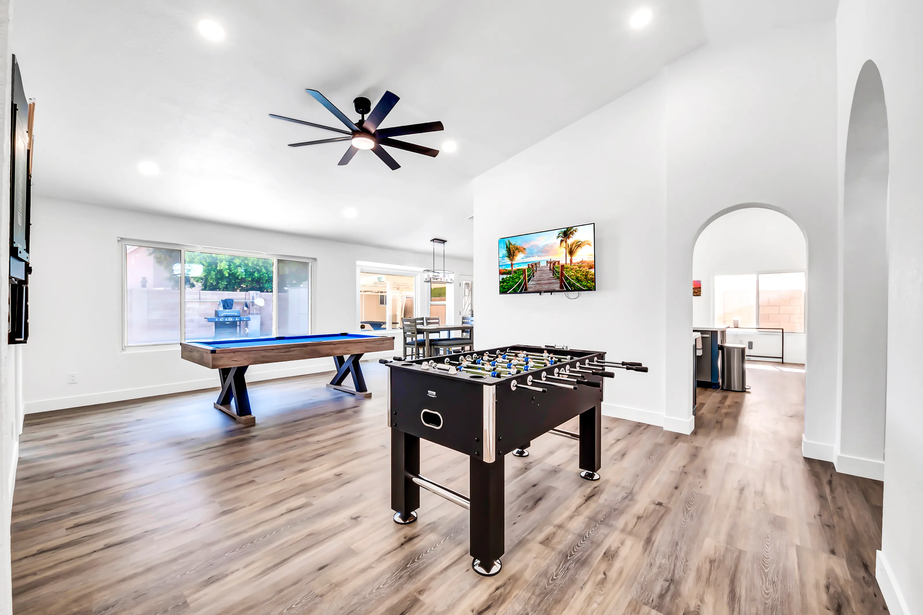 The home's shared recreation area with a pool table and foosball table in a bright, open community space.