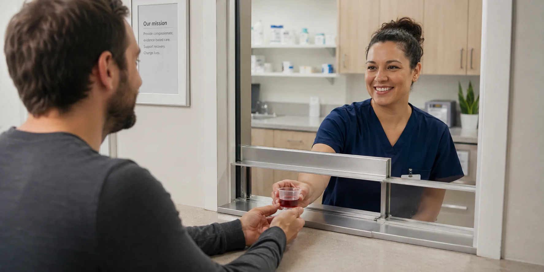 A nurse hands a small dosing cup through the medication window to a patient at AriseVida Care.