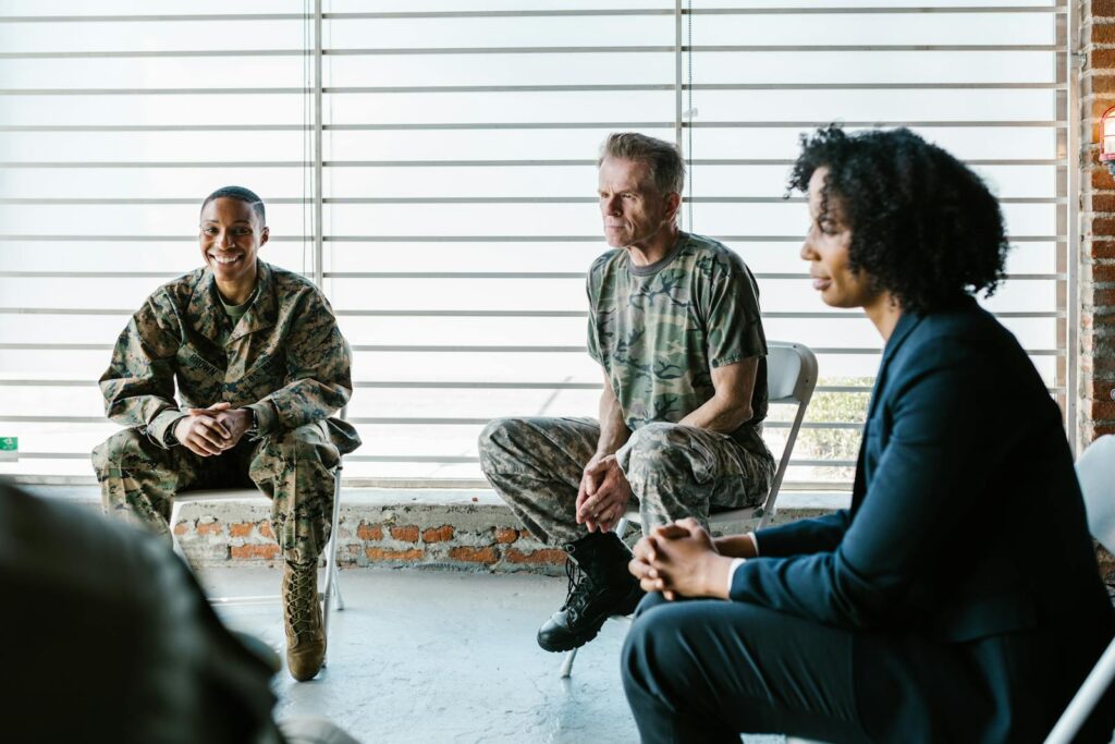 Military veterans engage in a supportive group therapy session with a mental health professional.